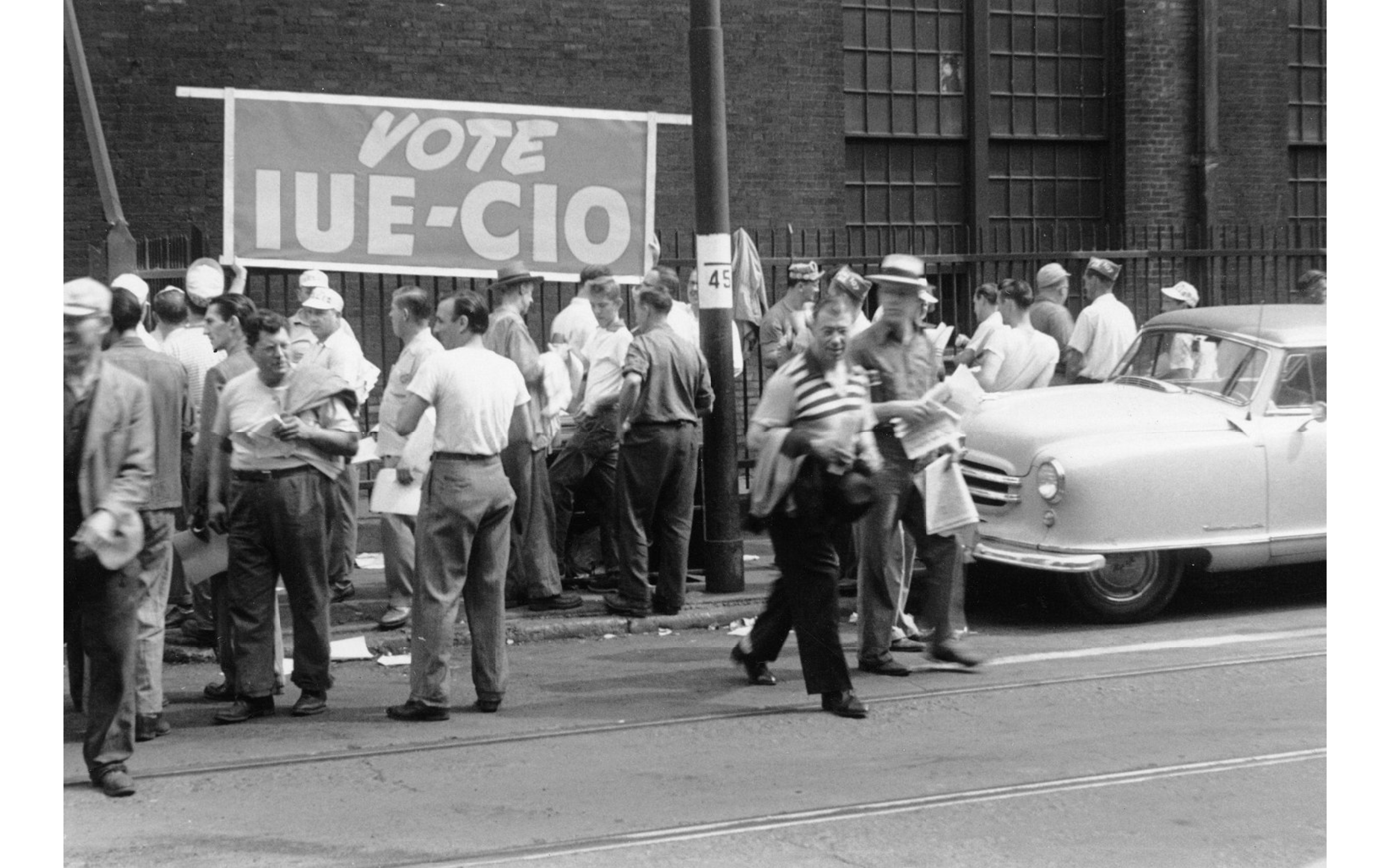 IUE CIO banner on side of Westinghouse plant while workers wait to vote, Pittsburgh, PA, 1949. From University of Pittsburgh digital collection.